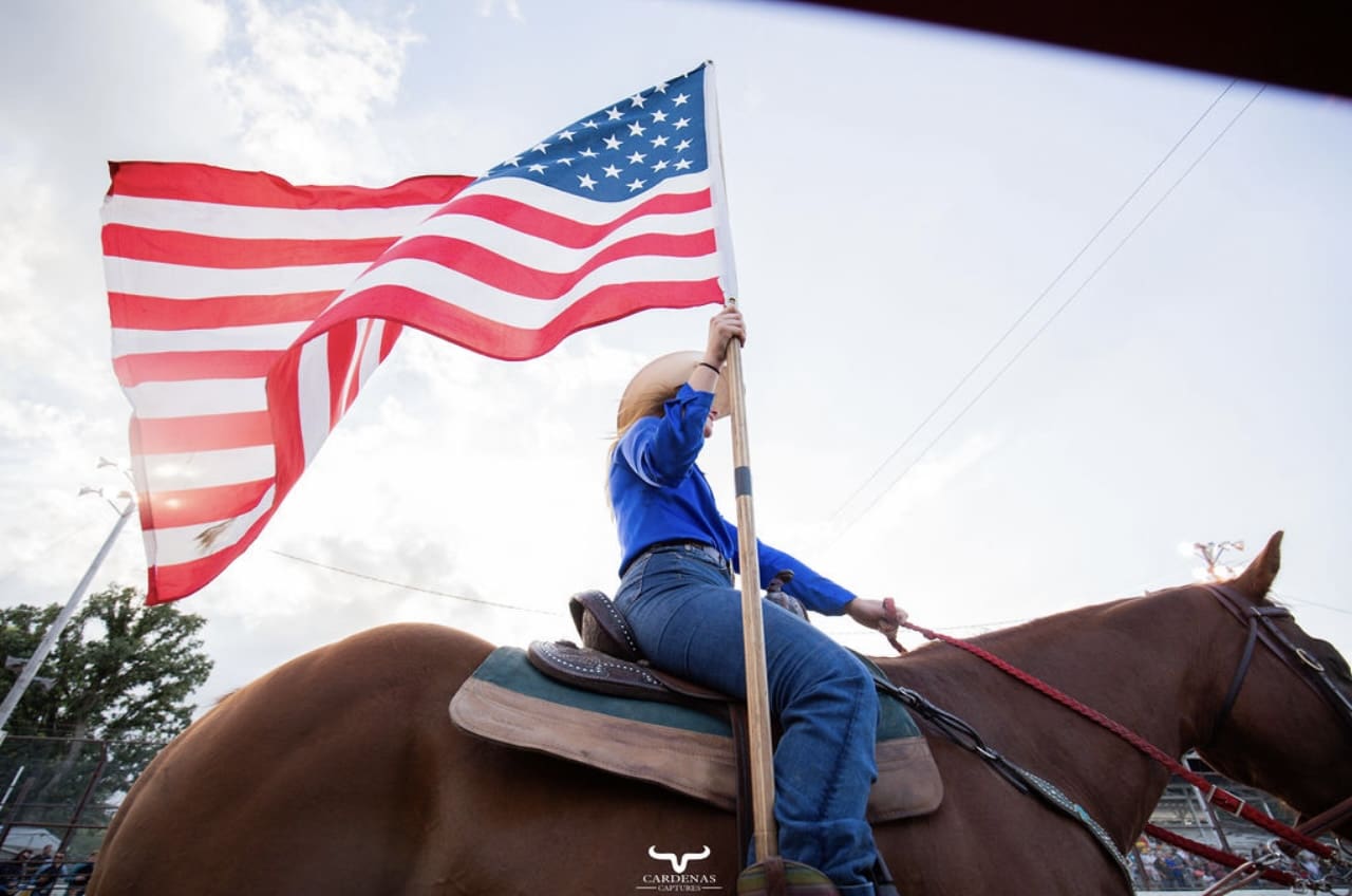 A person on horseback holding an american flag.